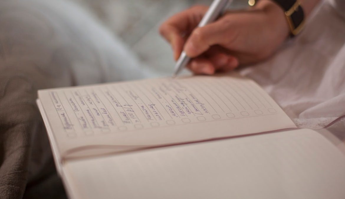 A close-up image of a person's hand writing in a notebook, emphasizing focus and creativity.