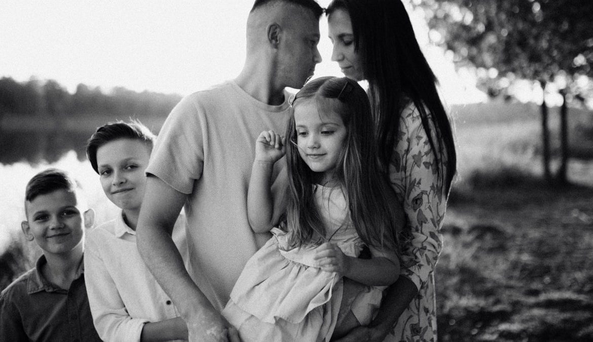 A serene black and white portrait of a family standing by a lake.