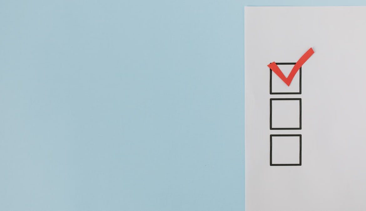 A minimalist checklist with a red checkmark on a blue background, providing ample copy space.